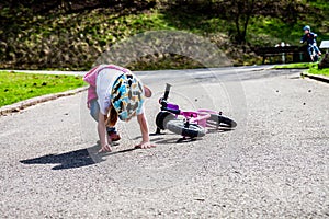 Cute little girl fallen off her bicycle outdoors