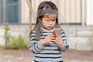 Cute little girl fascinated by a mobile phone