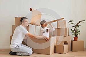 Cute little girl with father making ship with flag during relocation and playing sailors, daughter looking in spying glass,