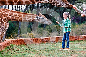 Cute little girl feeding giraffes in Kenya