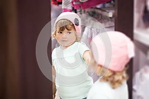 Cute little girl fiting on clothes in the shop.