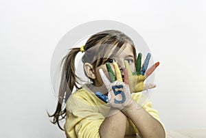 Cute little girl with the five number painted on the hand looking at camera - Little girl who is painting her hands with numbers