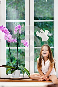 Cute little girl with flower sitting on windowsill of new pvc wi