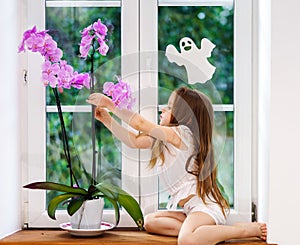 Cute little girl with flower sitting on windowsill of new pvc wi