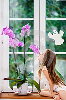 Cute little girl with flower sitting on windowsill of new pvc wi
