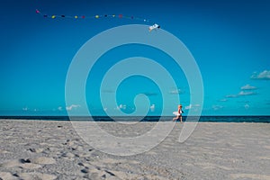 Cute little girl flying a kite at sky on beach