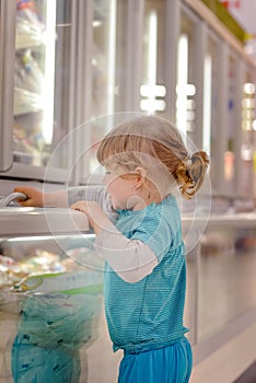 Cute little girl in a frozen aisle of a supermarket