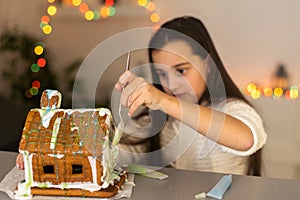 Cute little girl with gingerbread spooky house with festive icing and ghost shaped cookie. Happy Halloween