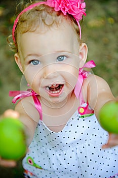 Cute little girl gives green apples