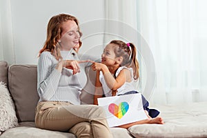 Cute little girl giving a heart-drawing to her mother