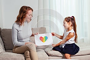 Cute little girl giving a heart-drawing to her mother