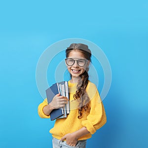 Cute little girl with glasses and books on background. Reading concept