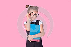 Cute little girl with glasses and books on pink background, space for text. Reading concept