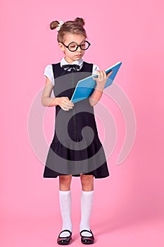 Cute little girl with glasses and books on pink background, space for text. Reading concept