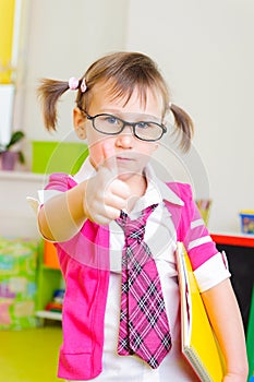 Cute little girl in glasses showing thumb up