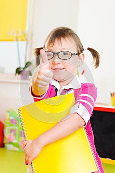 Cute little girl in glasses showing thumb up