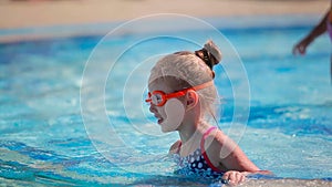 Cute little girl in goggles swimming in the swimming pool