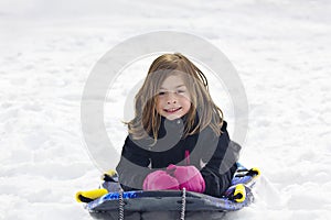 Cute Little Girl going snow sledding down a hill