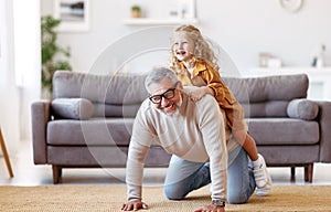 Cute little girl granddaughter playing and having fun with active positive grandfather at home