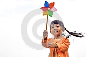 Cute little girl on grass in summer day holds windmill