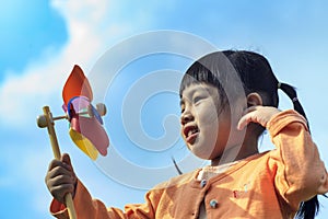 Cute little girl on grass in summer day holds windmill