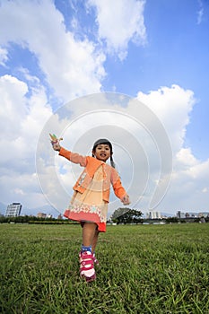 Cute little girl on grass in summer day holds windmill
