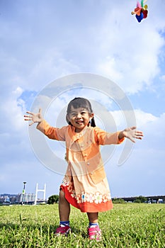 Cute little girl on grass in summer day holds windmill