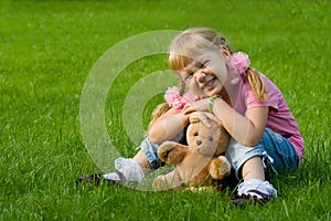 Cute little girl in grass with teddy bear.