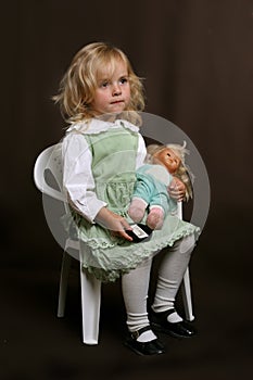 Cute little girl in green dress with doll