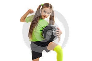 Cute little girl in green uniform playing with soccer ball