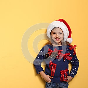 Cute little girl in handmade Christmas sweater on color background