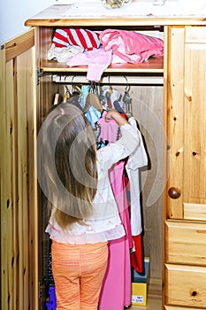 Cute little girl hanging up her clothes