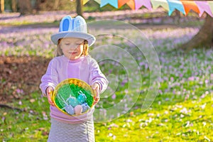 cute little girl in hat with rabbit ears o and a basket with Easter eggs at party in park