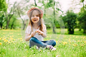 Cute little girl with hat siting on the grass.