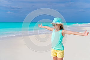 Cute little girl in hat walking at beach during caribbean vacation