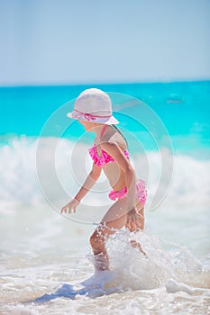 Cute little girl in hat walking at beach during caribbean vacation