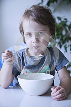 Cute little girl having breakfast muesli with milk at home in th