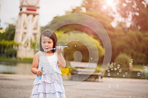 Cute little girl having fun with blowing soap bubbles