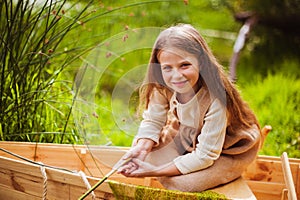 Cute little girl having fun in a boat by a river