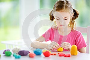 Cute little girl having fun with colorful modeling clay at a daycare