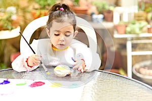 Cute little girl having fun, coloring with brush, playing and painting. Preschooler with paint at garden.