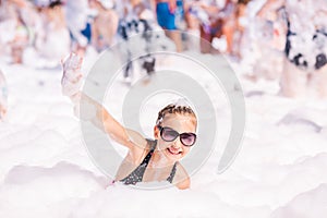 Cute little girl having fun at foam party.