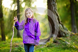 Cute little girl having fun during forest hike on beautiful autumn day