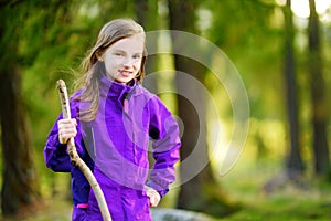 Cute little girl having fun during forest hike on beautiful autumn day in Italian Alps