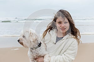 cute little girl having fun with her dog in vacation at beach