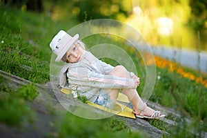 Cute little girl having fun outdoors on sunny summer evening. Child exploring nature