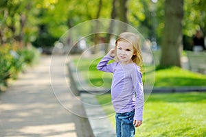 Cute little girl having fun outdoors on sunny summer evening. Child exploring nature