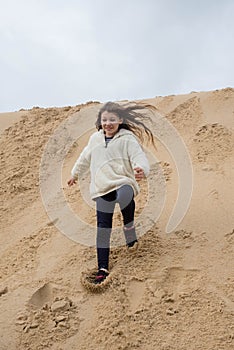 cute little girl having fun playing in the sand dunes