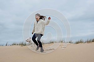 cute little girl having fun playing in the sand dunes with her little dog