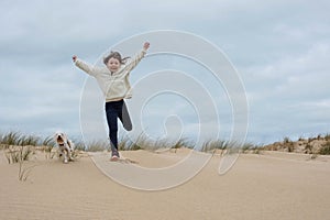 cute little girl having fun playing in the sand dunes with her little dog